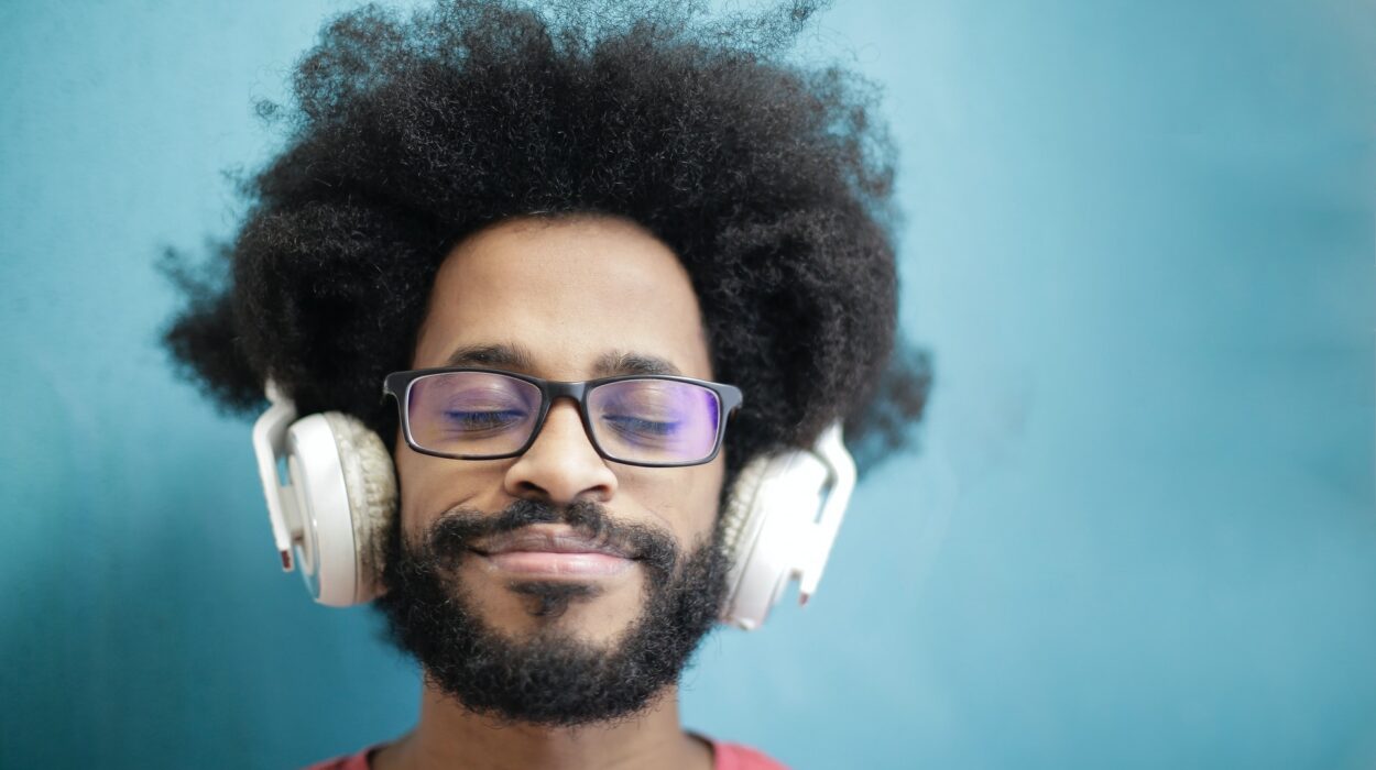 Homem aparentemente de Home Office, sentado em frente do computador usando óculos de grau e fones de ouvido. Sua expressão é de tranquilidade.